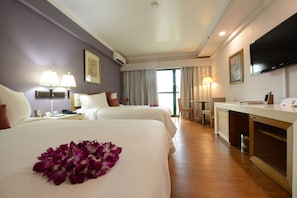 A hotel room with two beds, a desk, a TV, and a bathroom.