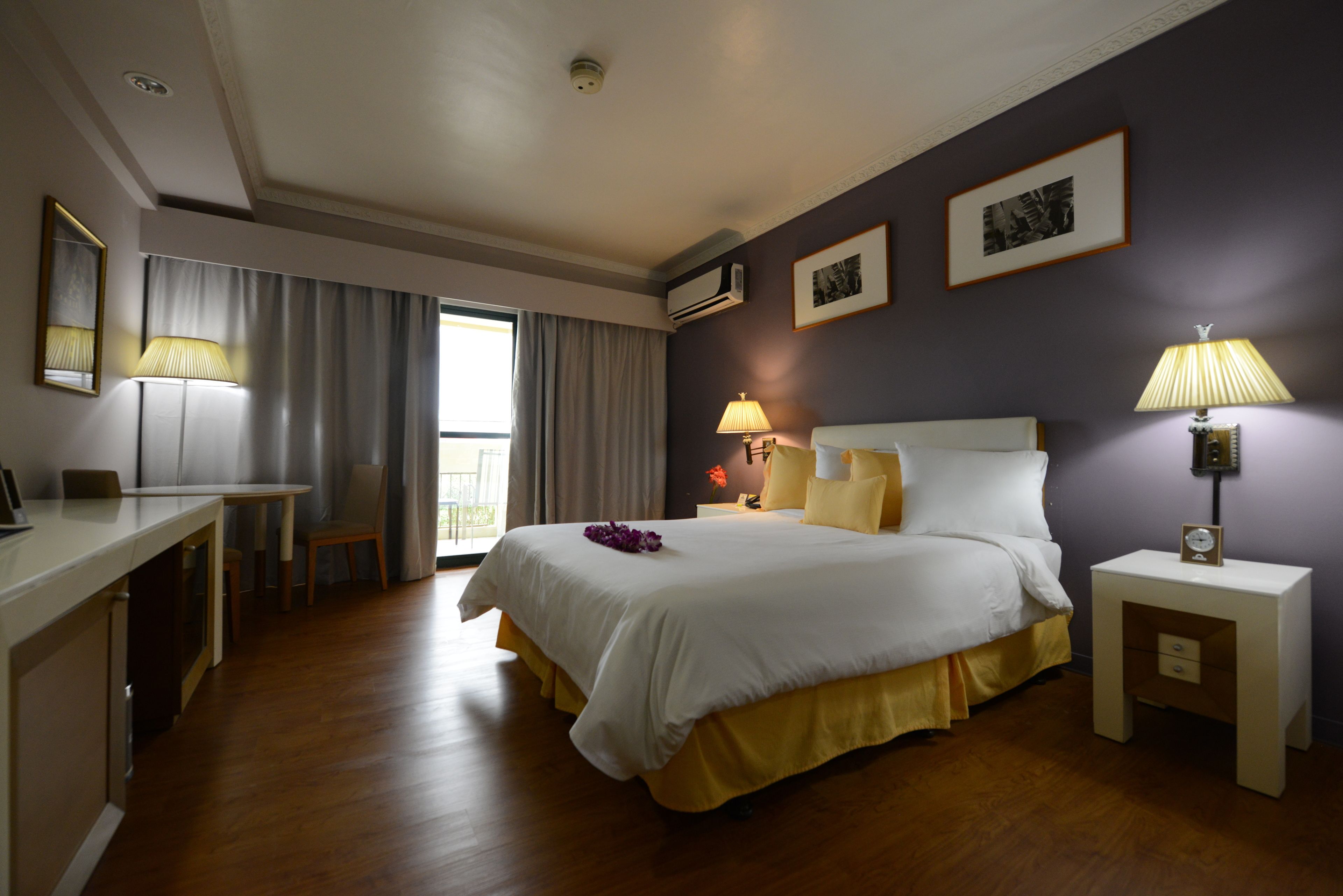A hotel room with a bed, bedside tables, a desk, and a chair.