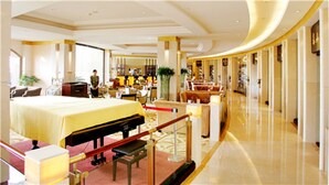 A hotel lobby with a reception desk, seating area, and a large bed in the foreground. - Ramada Plaza Taian (Tai'an)