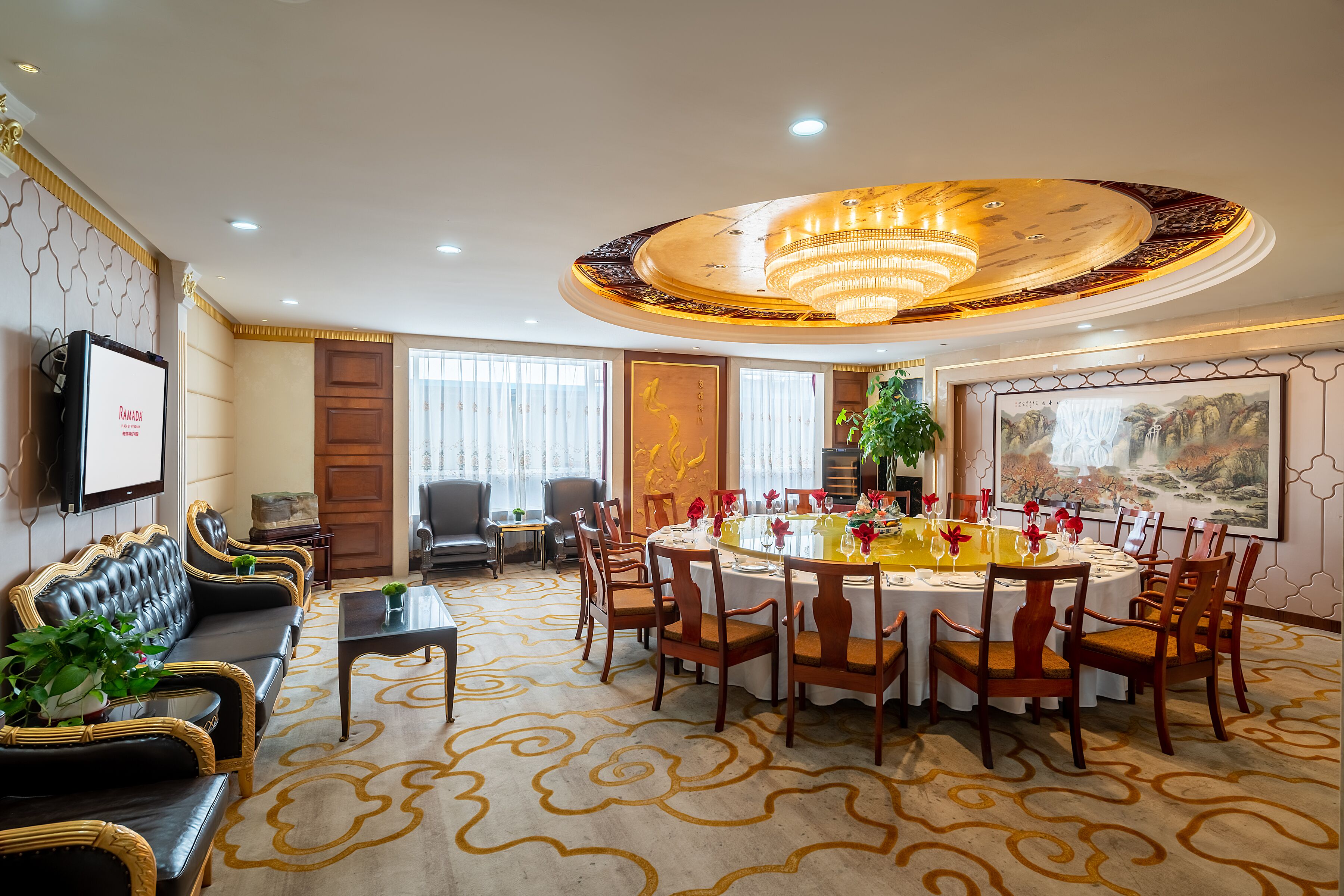 A conference room with a round table, chairs, a sofa, and a TV screen.