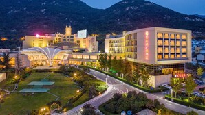 A hotel with a modern architectural design, featuring a prominent glass facade and a landscaped courtyard. - Ramada Plaza Taian (Tai'an)