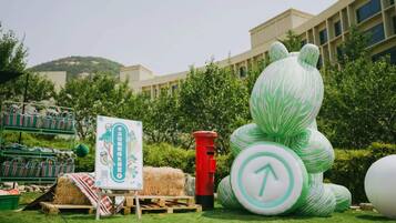 Un espacio al aire libre con césped, una escultura grande verde y blanca a rayas, un hidrante rojo y un letrero con caracteres chinos.