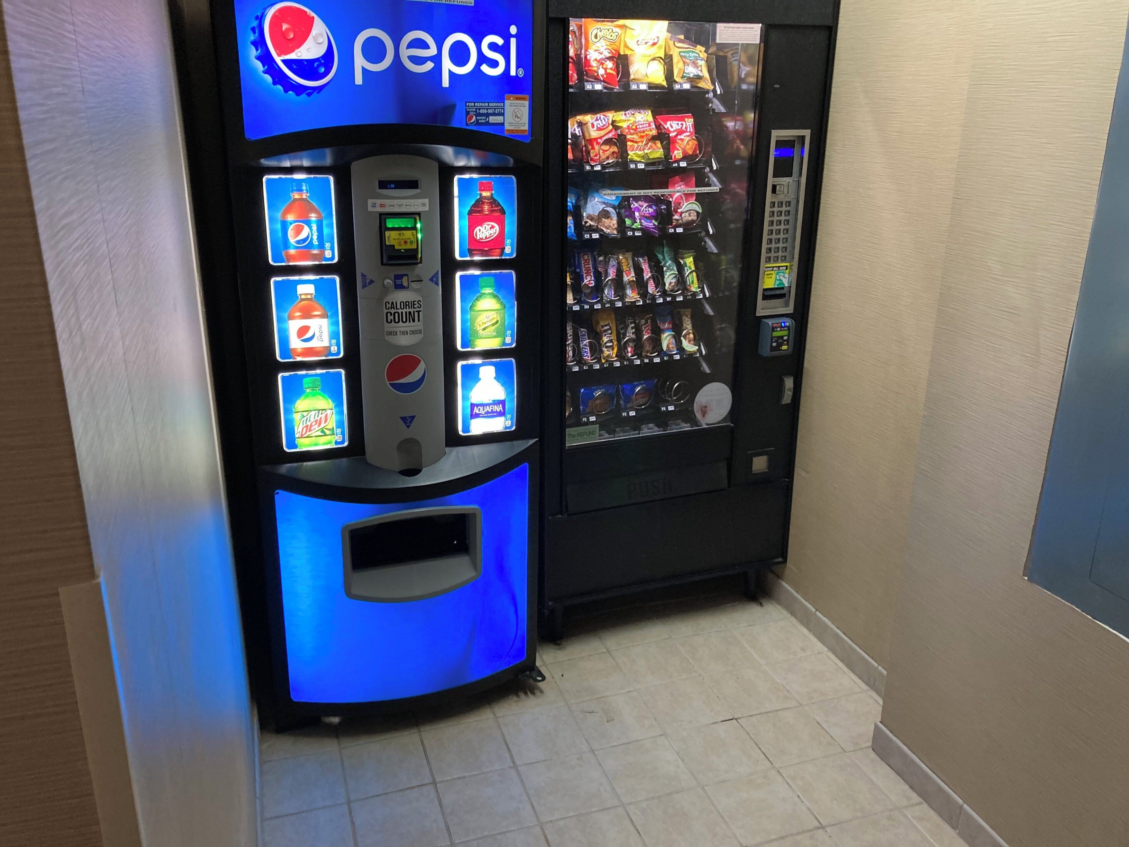 Máquina expendedora con el logotipo de Pepsi y una variedad de aperitivos y bebidas.