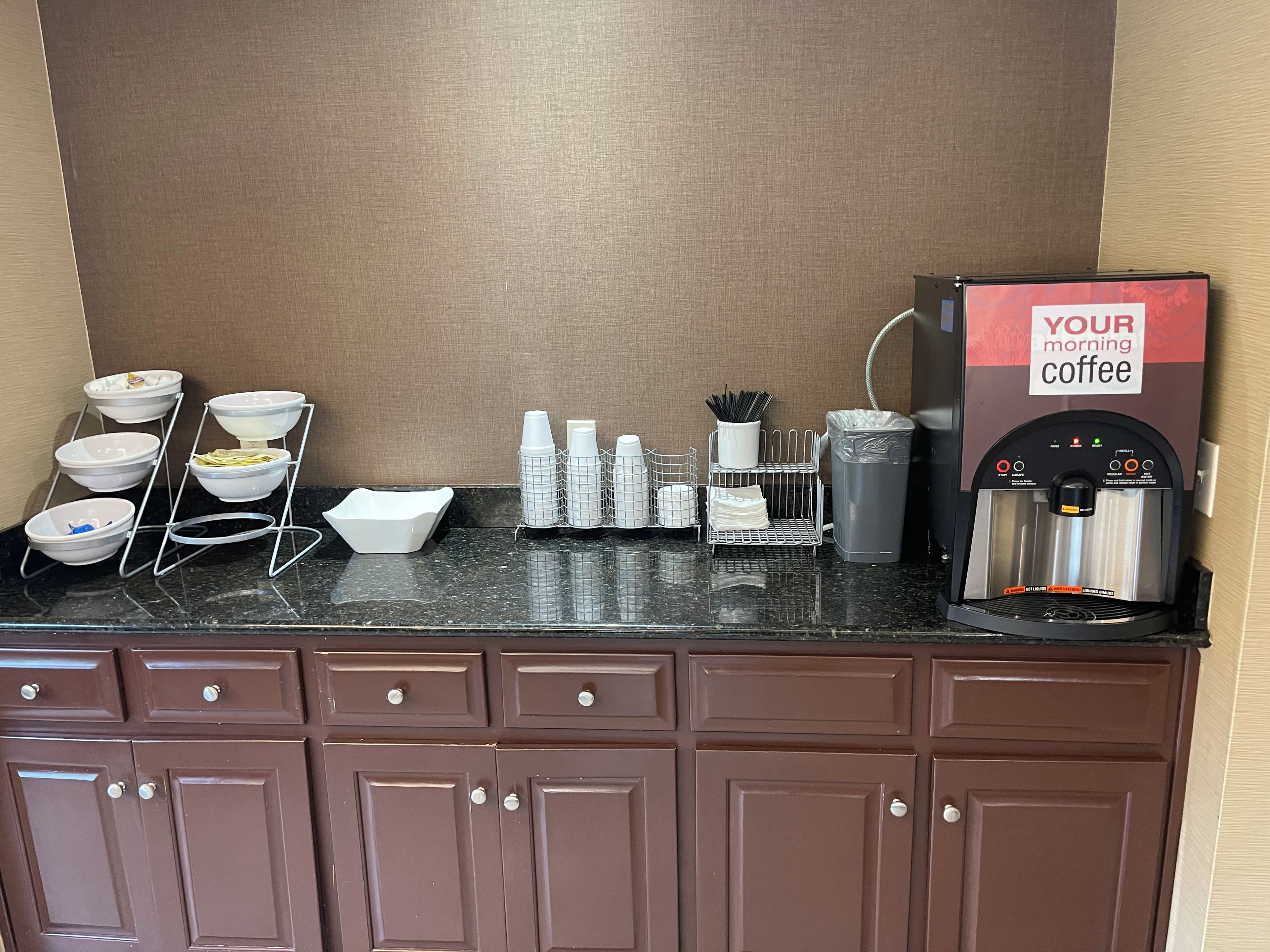 A coffee station with a coffee machine, condiment dispensers, and a bowl rack.