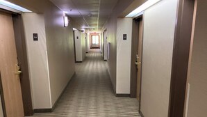 Un pasillo de hotel con pisos alfombrados, puertas a ambos lados e iluminación en el techo.