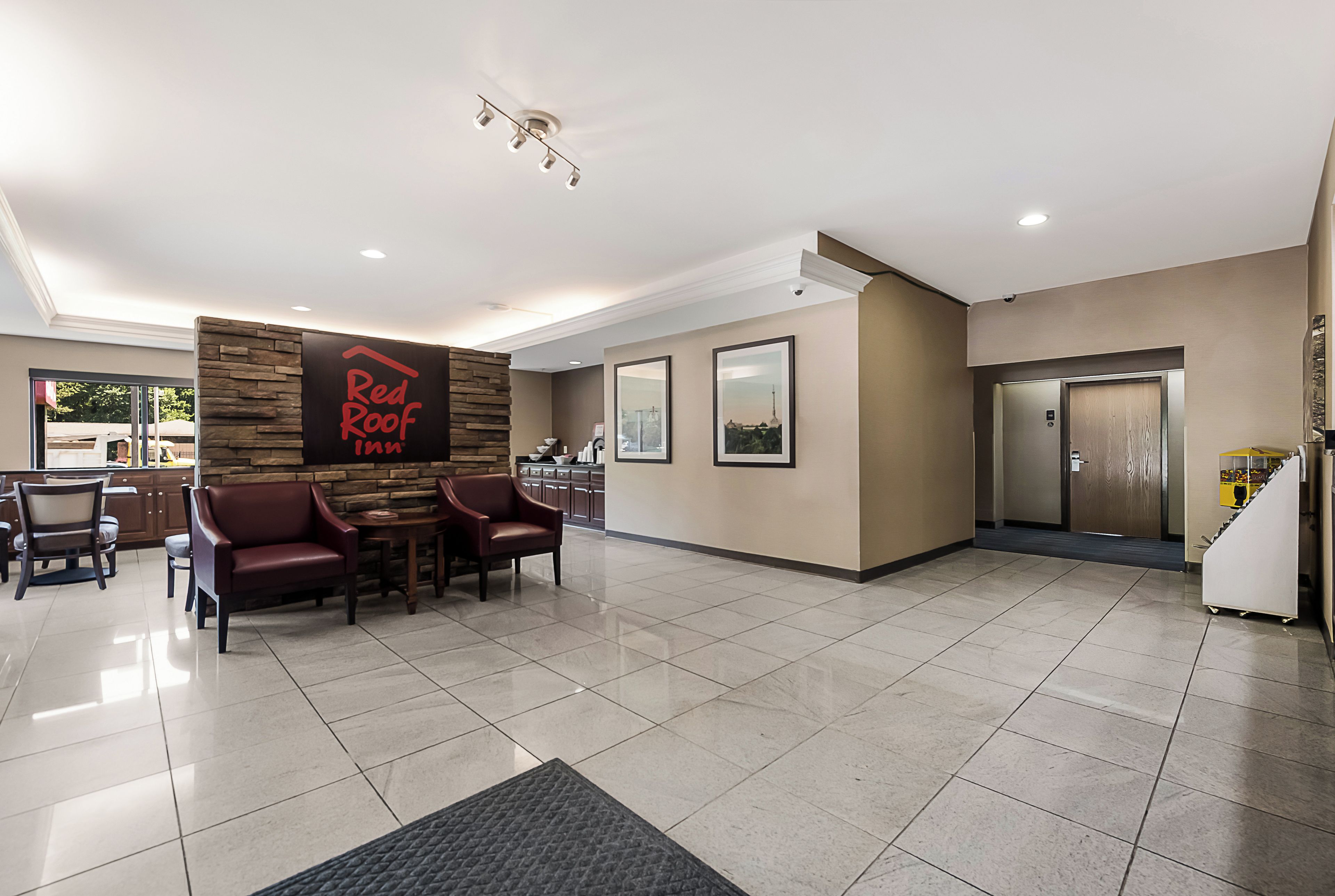 A hotel lobby with a reception desk, seating area, and a staircase leading to the elevators.