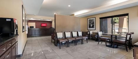 Un hall d’hôtel comprenant un comptoir d’accueil, un espace salon et une grande fenêtre.