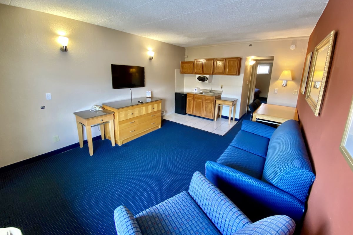 A compact living space with a kitchenette, a flat-screen TV, a sofa, and a desk.