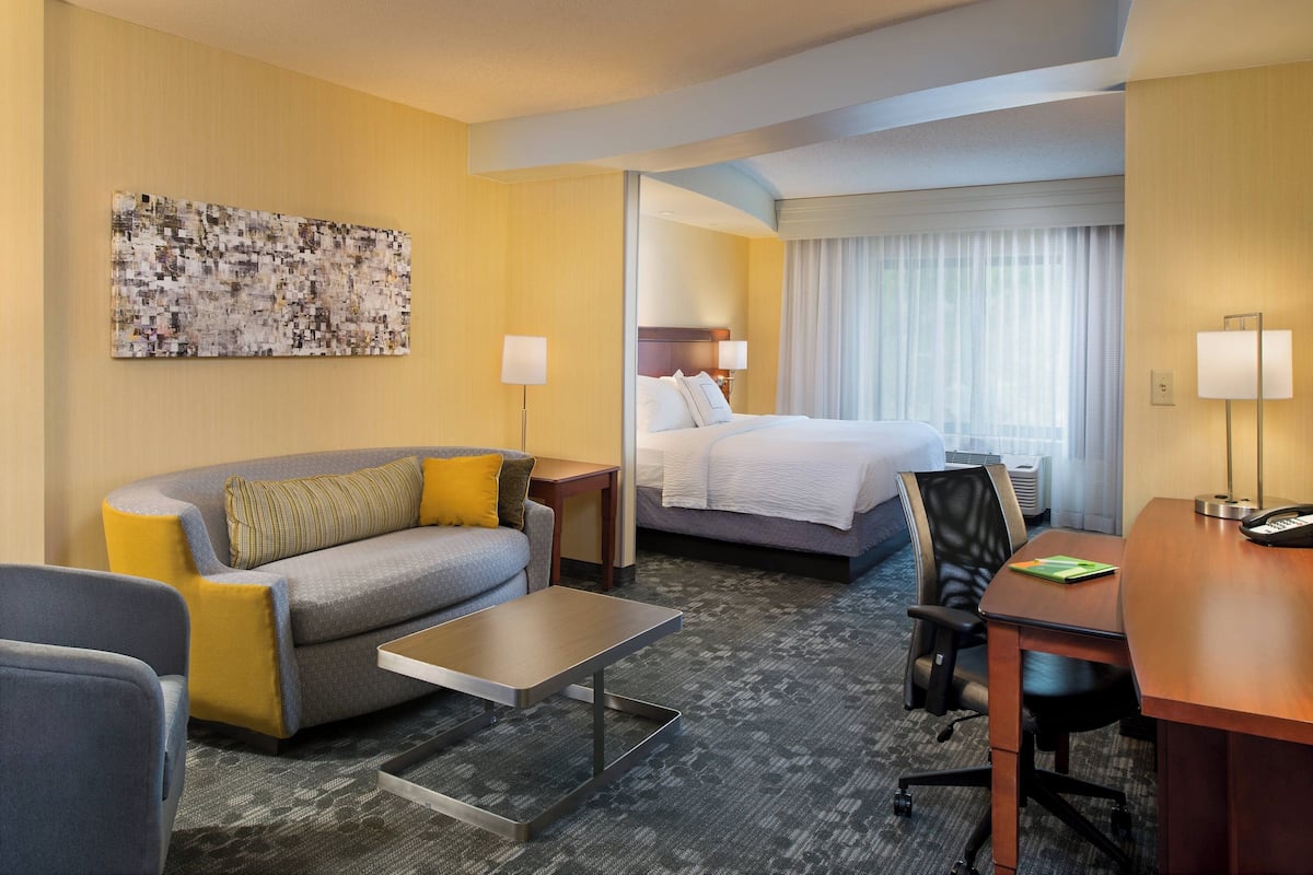 Habitación de hotel con sofá, cama, escritorio y un ventanal grande.