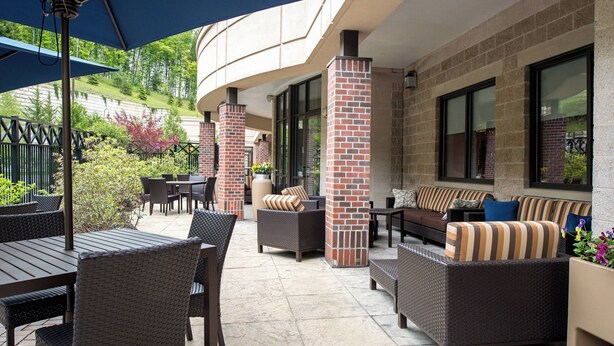 An outdoor patio area with wicker furniture, brick pillars, and large windows. - Courtyard by Marriott Hanover Lebanon (Lebanon)
