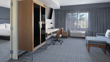 A hotel room with a bed, a desk, a chair, a wardrobe, a TV, and a window with curtains.