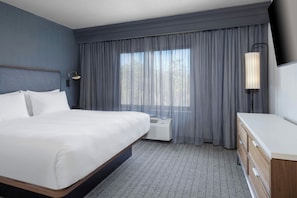 A hotel room with a bed, a desk, a lamp, an air conditioning unit, and a window with curtains. - Courtyard by Marriott Hanover Lebanon (Lebanon)