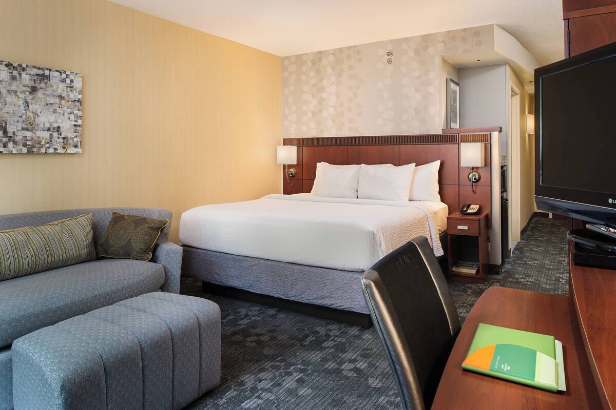 Una habitación de hotel con cama, sofá, escritorio y televisor.
