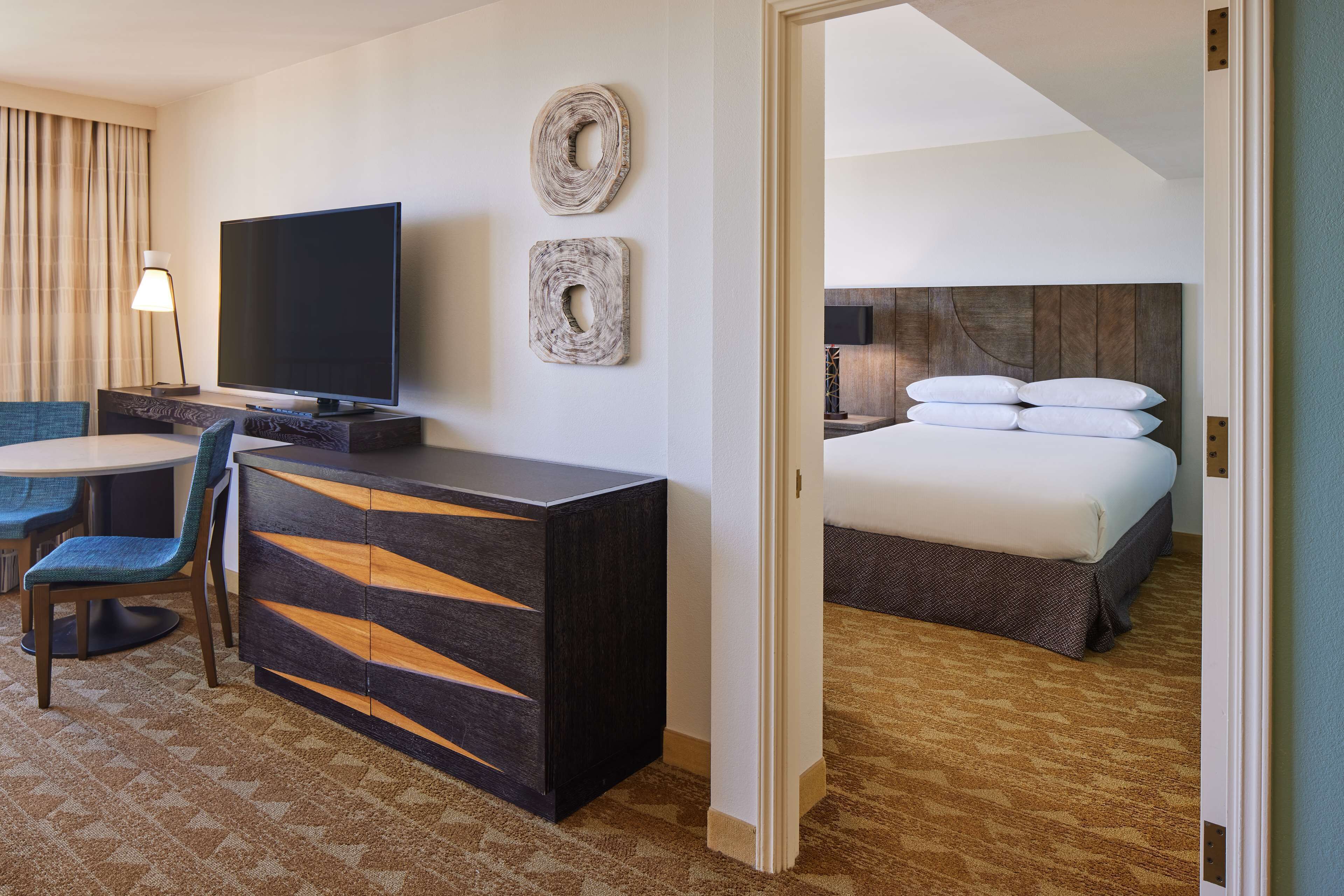 A hotel room with a bed, a TV, a desk, and a chair.