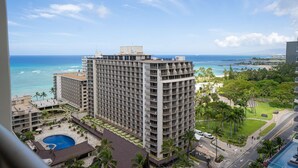 A high-rise hotel with multiple balconies, a swimming pool, and a view of the ocean.