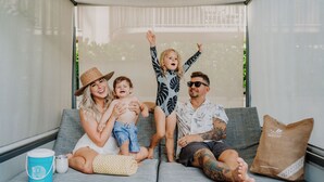 Una familia de cuatro personas en un sofá gris, con vistas al exterior.