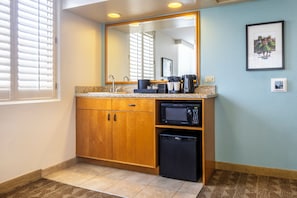 A bathroom with a wooden vanity, a microwave, and a small sink.