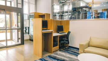Un espacio de oficina moderno con un escritorio, computadora y silla de oficina. Hay un sofá y una pequeña mesa en la habitación.