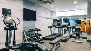 Une salle de sport équipée de tapis de course, d’haltères et d’autres appareils d’exercice.