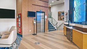 Un hall d’entrée moderne avec un comptoir d’accueil, un escalier et un ascenseur fixé au mur.