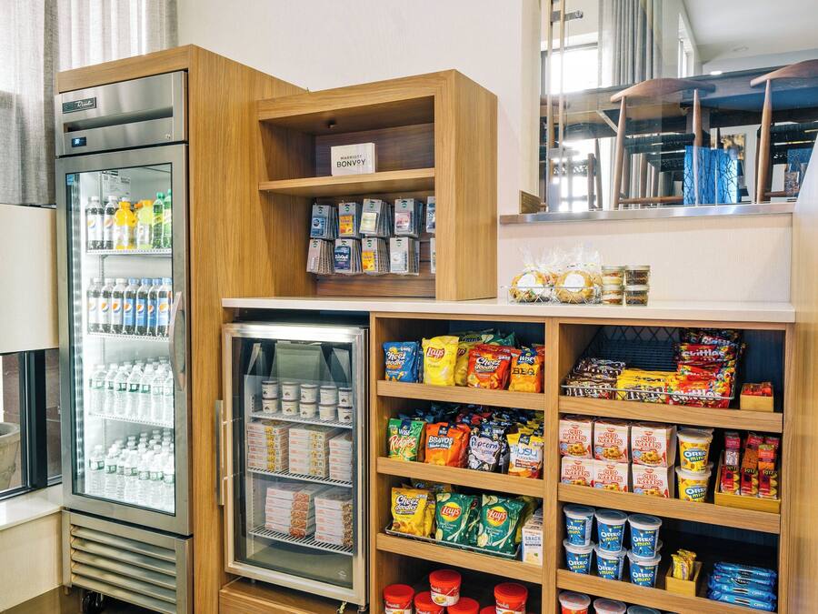 A self-service snack and beverage area with refrigerated drinks, a variety of packaged snacks, and a selection of frozen desserts.