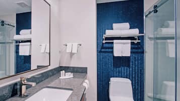 A modern bathroom with a large mirror, a sink, a toilet, and a glass shower enclosure.