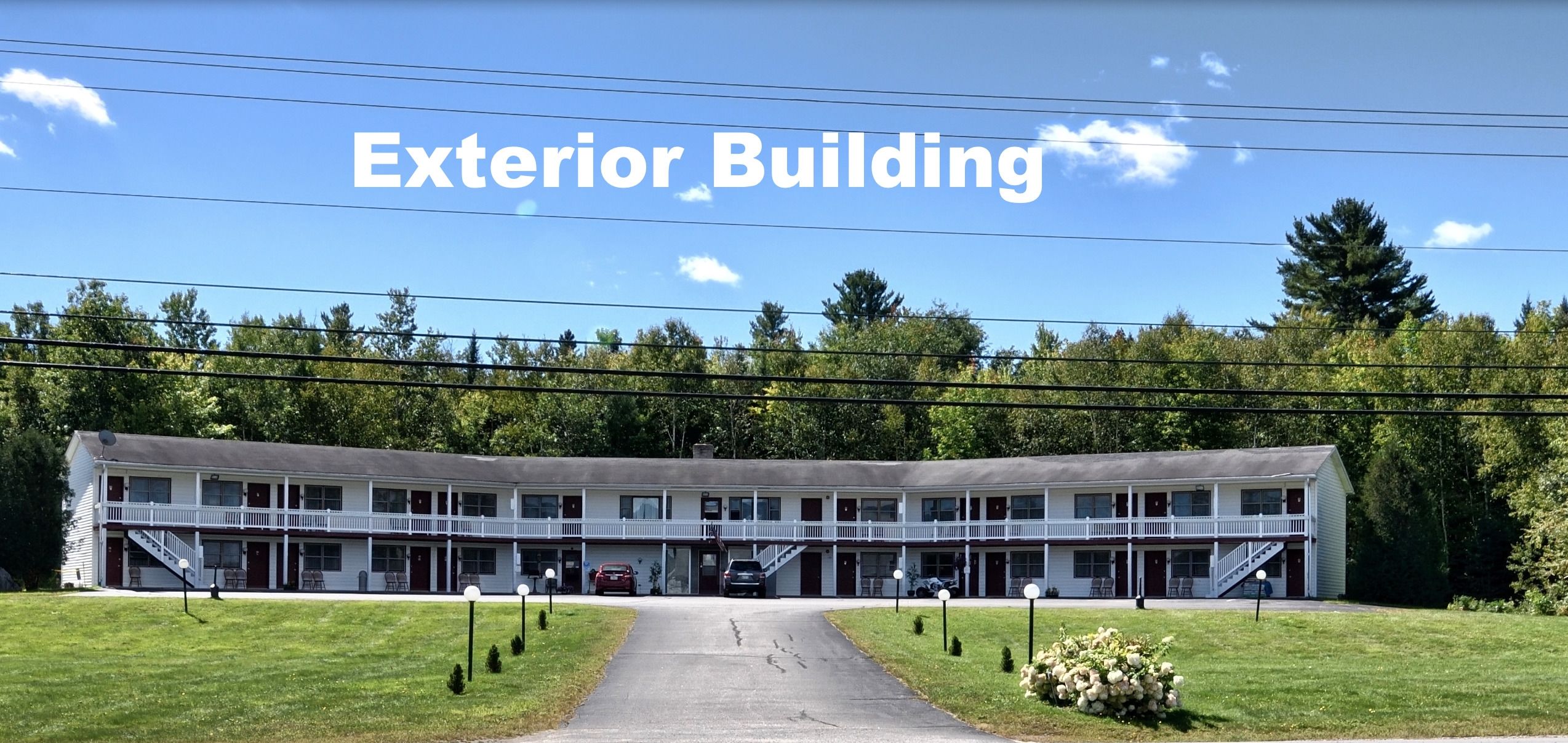 A two-story motel with a central corridor, multiple balconies, and a parking area.