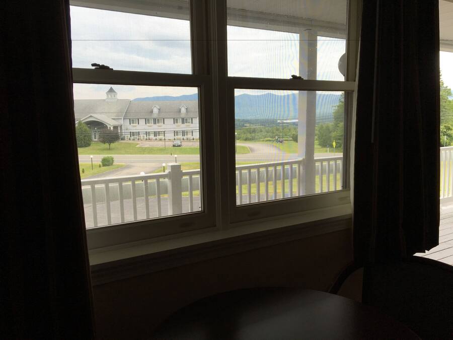 A room with a large window overlooking a road and a building.
