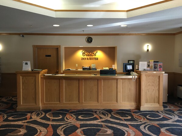 A hotel reception desk with a sign reading "Caliber Inn & Suites". - Cabot Inn & Suites (Lancaster)