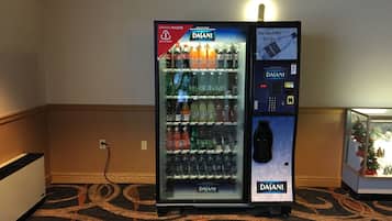 Un distributeur d’eau Dasani doté d’un terminal de paiement numérique, situé dans le hall d’un hôtel, avec un tapis à motifs et une petite décoration de Noël.