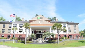 A hotel with a central entrance, palm trees, and a flag.
