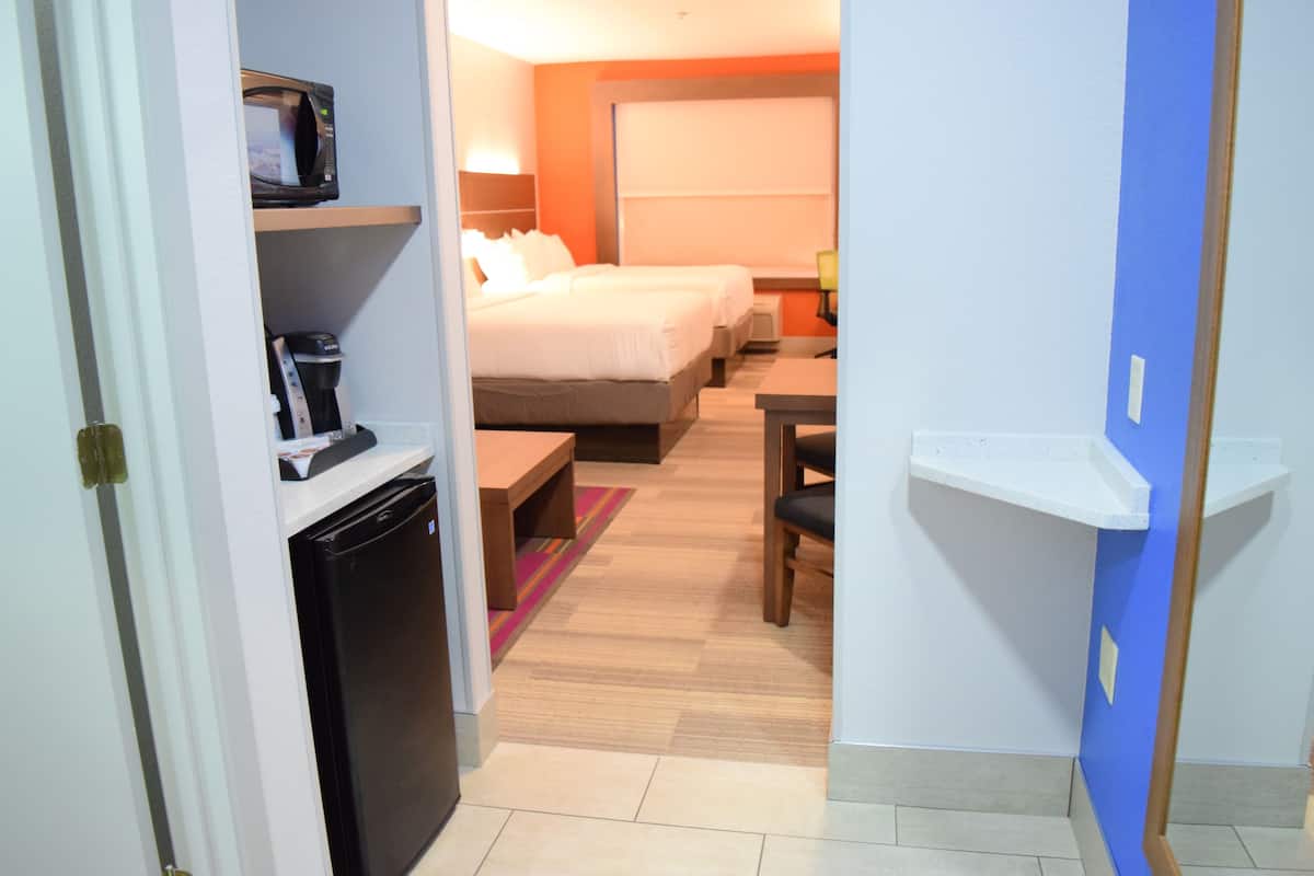 Una habitación de hotel con una cama, un escritorio, una silla, un microondas y una cafetera.