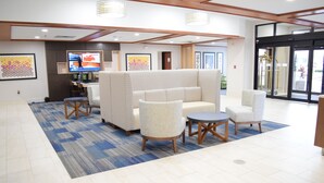 A lobby with a seating area, a reception desk, and a television screen.