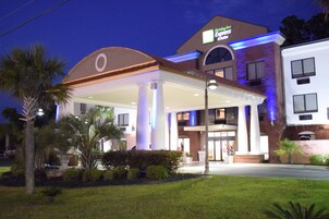 A Holiday Inn Express hotel with a covered outdoor area, palm trees, and a brick facade.