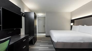 A hotel room with a bed, a TV, a dresser, and a door leading to a hallway.