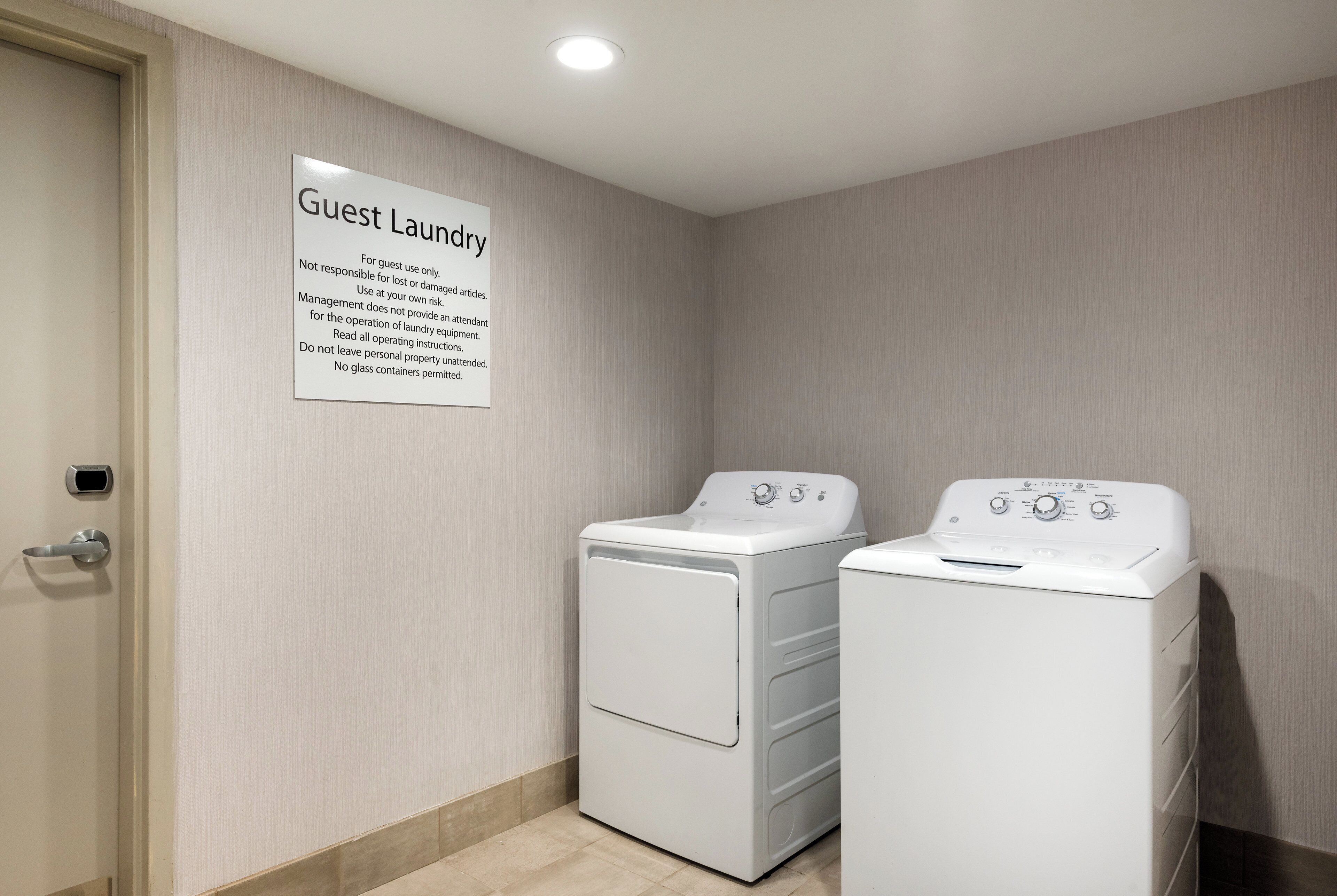 A laundry room with two white washing machines and a sign indicating it's for guest use only.