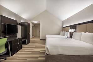 A hotel room with a bed, a desk with a chair, a television, and a door leading to another room.