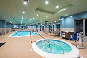 Ein Hotelpoolbereich mit zwei Pools, einem Rettungsschwimmerstand und einer Handtuchausgabe.