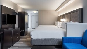Une chambre d’hôtel avec un lit, une télévision, un bureau et une chaise bleue.