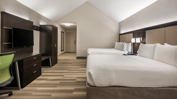 Une chambre d’hôtel avec un grand lit, un bureau avec une chaise, une télévision et un dressing.