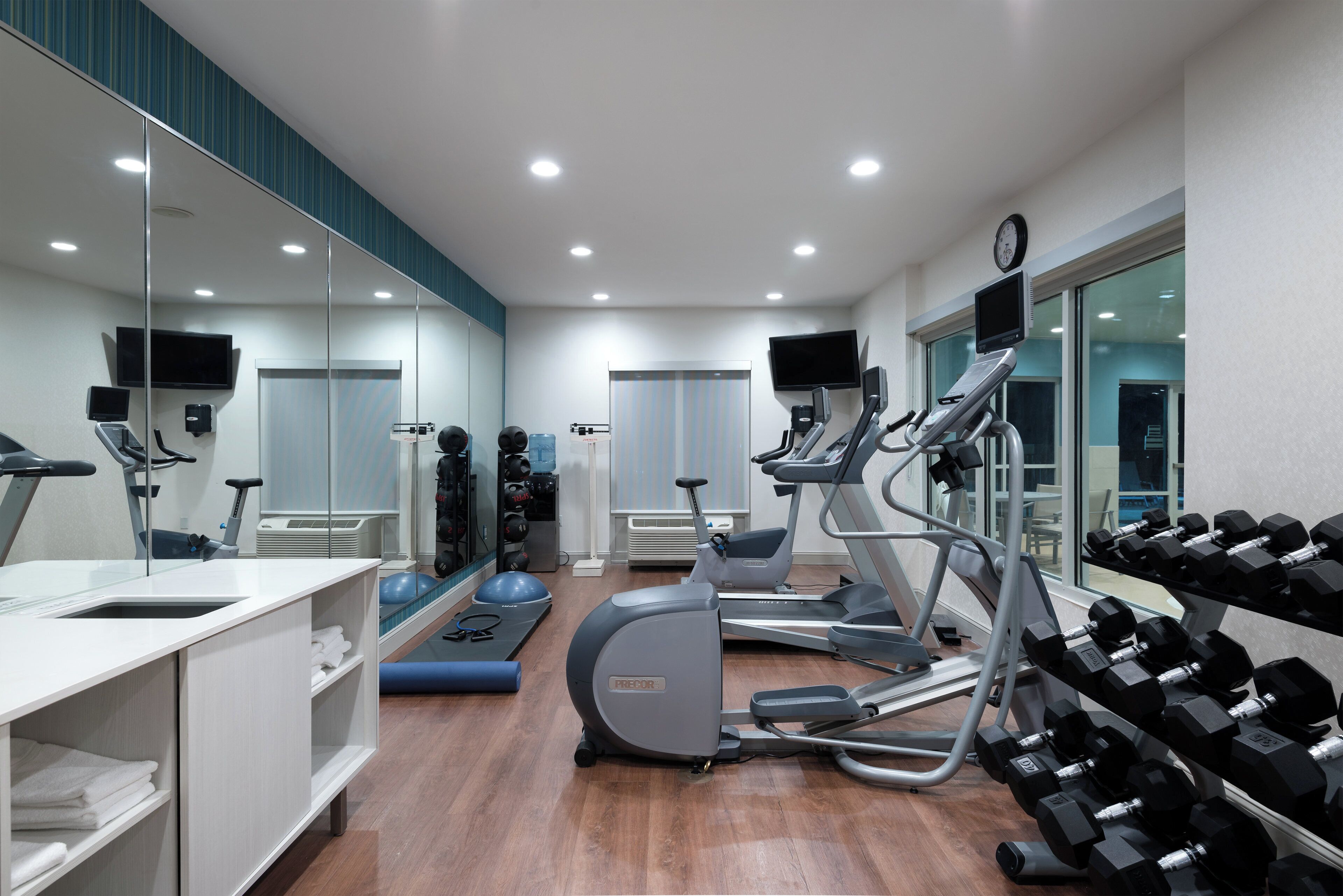 A modern gym with cardio equipment, weightlifting area, and mirrors.