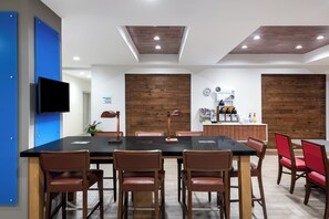 Una sala de conferències amb una taula llarga, cadires, un racó de cafè i un rellotge a la paret.
