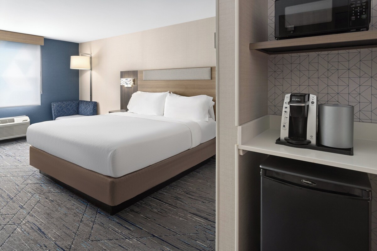 A hotel room with a bed, a coffee maker, a microwave, and a mini-fridge.