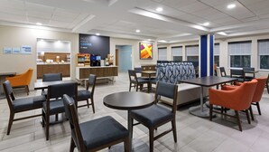 A modern dining area with round tables and chairs, a coffee station, and a view of the city. - Holiday Inn Express Hotel & Suites Freeport by IHG (Freeport)