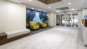A reception area with a modern design, featuring a seating area with yellow chairs, a reception desk, and a large wall mural. - Holiday Inn Express Hotel & Suites Freeport by IHG (Freeport)
