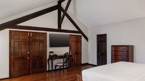 A bedroom with a bed, a desk, a chair, and a dresser. - Chateau Hotel (New Orleans)