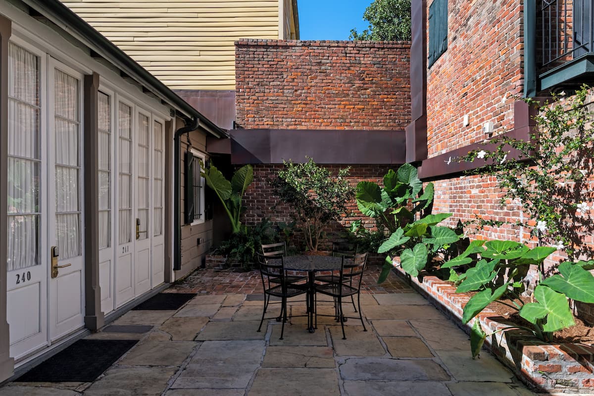 A patio with a table and chairs, a brick wall, and a door with the number 240.