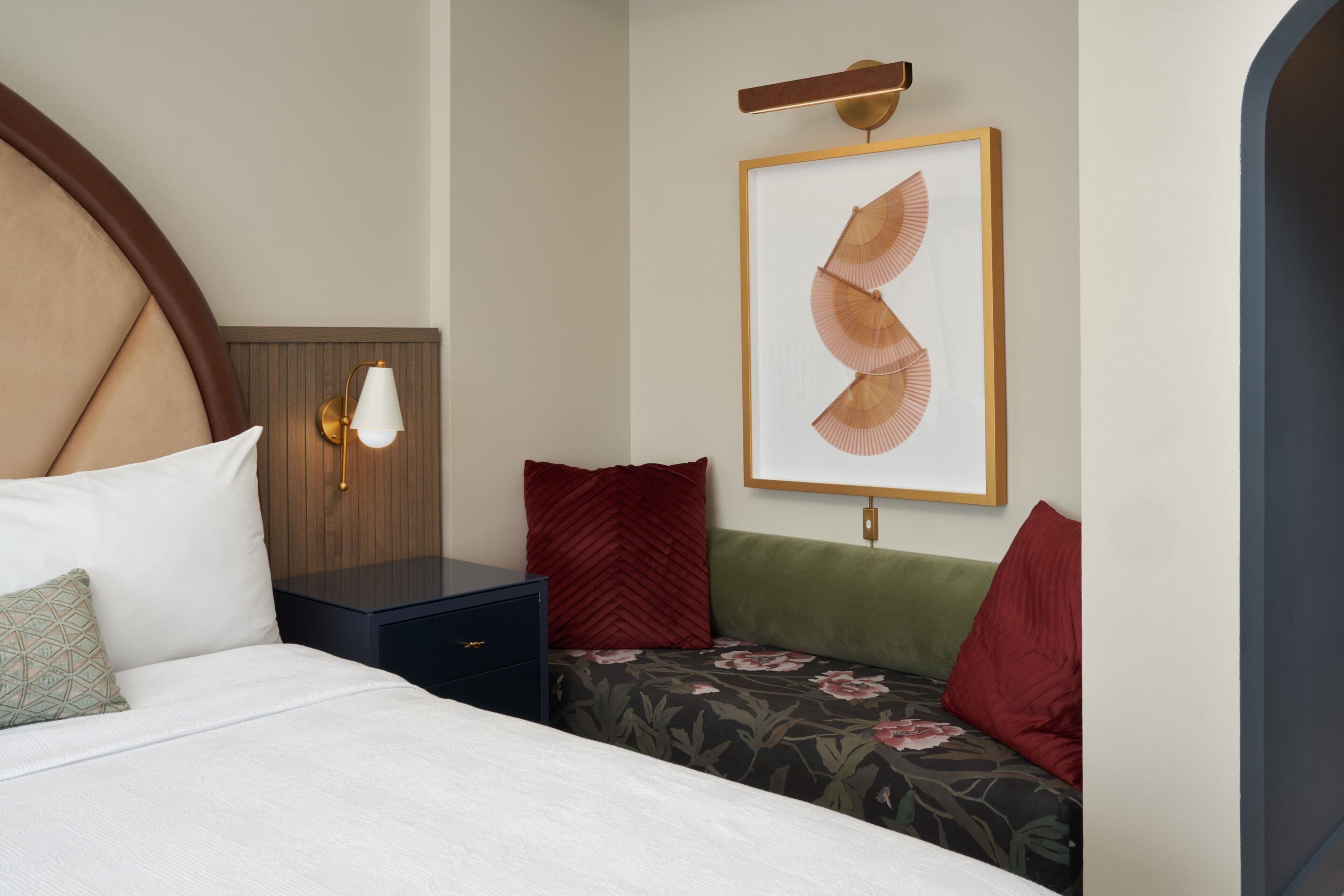 Een keurig opgemaakt slaapkamer met een bed, nachtkastjes en een wandlamp.