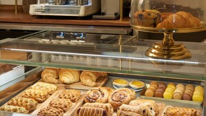 A bakery display case with various pastries and a coffee machine in the background. - Hotel Vesper, Houston, a Tribute Portfolio Hotel (Houston)