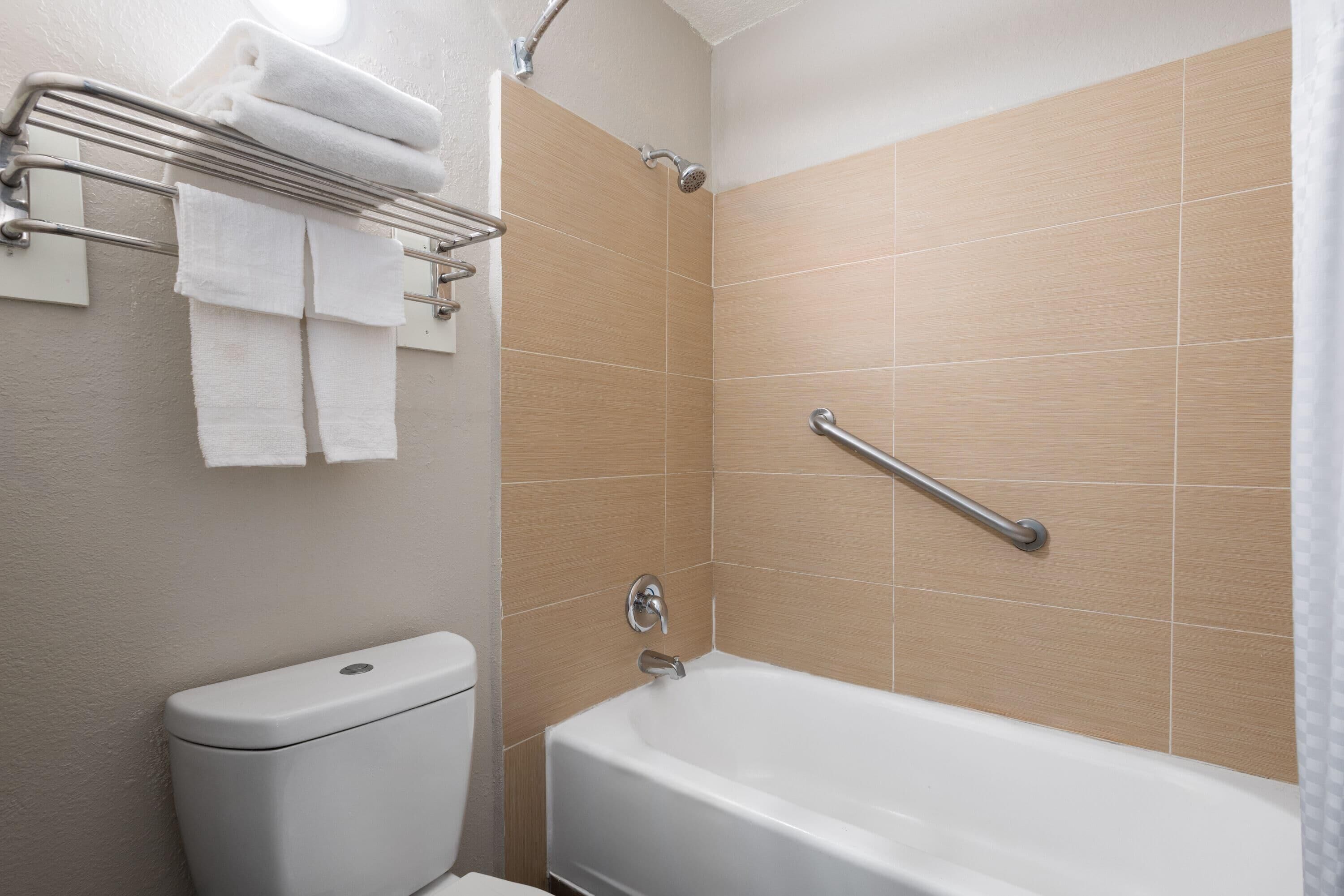 A bathroom with a bathtub, a toilet, and a towel rack.